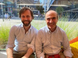 Christof Neuner, Senior Investment Manager bei Tauros Capital sitzt links von Carl Ludwig Schönfeldt, Co-Gründer und Geschäftsführer von Curawel auf einer Bank am Erste Campus